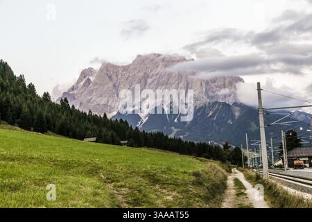 Eine wunderschöne Bergkette Zugspitze mit einem Zuggleis durch sie. Das Bahngleis befindet sich auf der rechten Seite des Gebirges, und es Stockfoto