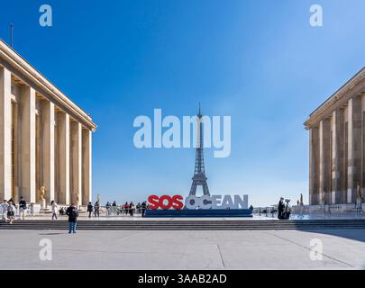 Paris, Frankreich - 03 31 2025: Blick auf den Eiffelturm, die Trocadero Esplanade und SOS Ocean Slogan und die Menschen in der Nähe Stockfoto