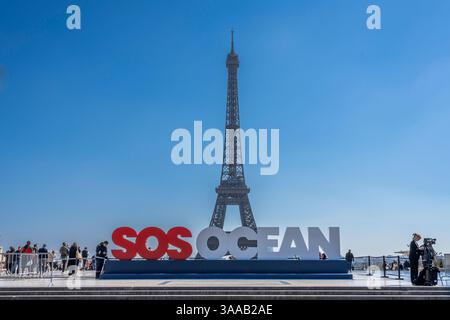 Paris, Frankreich - 03 31 2025: Blick auf den Eiffelturm, die Trocadero Esplanade und SOS Ocean Slogan und die Menschen in der Nähe Stockfoto