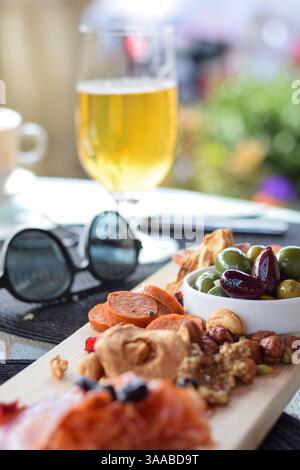 Wurstplatte mit Räucherfleisch, getrockneten Früchten und Oliven auf einem Terrassentisch des Restaurants Stockfoto