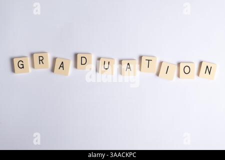 Wortgraduierung aus hölzernen Buchstabenfliesen auf sauberem weißem Hintergrund. Ideal für Bildungs-, Schulungs- und Feiertagsthemen. Stockfoto