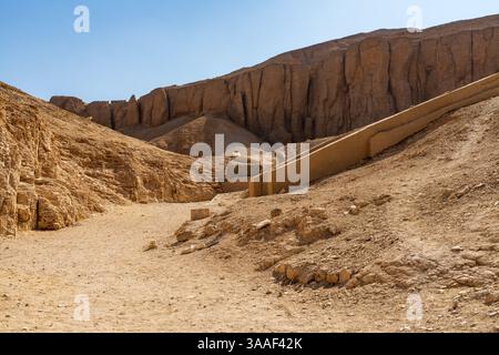 Die trockene Landschaft des Tals der Könige in Ägypten, bekannt für seine alten Gräber, unter einem klaren blauen Himmel. Stockfoto