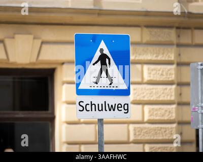Schulweg in Osterreich. Deutsche Sprache auf der Beschilderung. Fußgängerüberquerung neben einem Schulgebäude. Achten Sie auf den Quersteg. Stockfoto