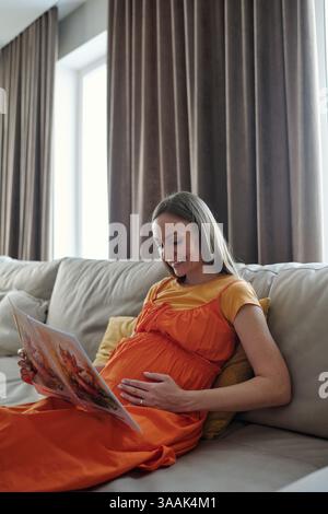 Glückliche Schwangere Frau, Die Das Magazin Liest Stockfoto
