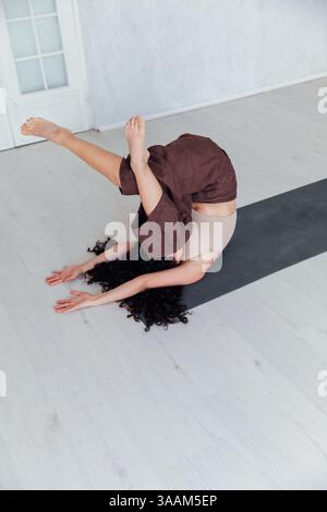 Yogi-Frau Brünette, die Asana-Gymnastik auf dem Boden im Flur macht Stockfoto