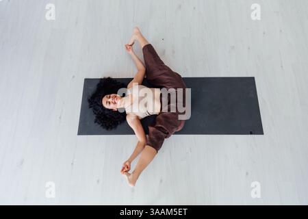 Yogi-Frau Brünette, die Asana-Gymnastik auf dem Boden im Flur macht Stockfoto