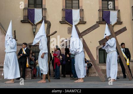 30. März 2018 - Queretaro, Mexiko - die Buße mit Kapuze tragen hölzerne Kreuze, während sie am Karfreitag während der Karwoche die Prozession der Stille durch die Straßen beginnen. Die Pönitenten, bekannt als Nazarener, tragen die schweren Kreuze und Schleppketten in einem vierstündigen marsch zur Erinnerung an die Passion Christi. (Bild: © Richard Ellis Via ZUMA Wire) Stockfoto