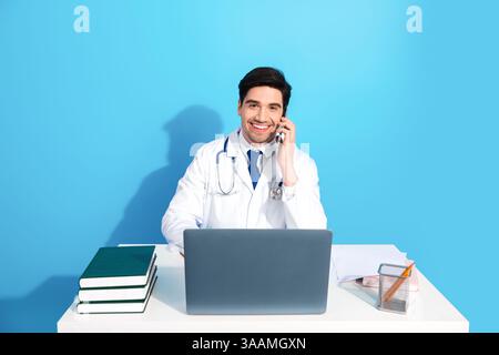 Männlicher Arzt mit Laptop und Telefon in hellblauem medizinischen Büro Arbeitsplatz Stockfoto