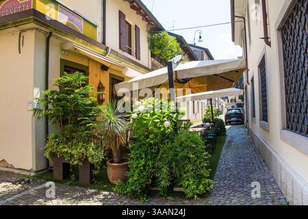 Udine, Italien - 9. Juli 2024. Eine kleine Bar mit überdachtem Außenbereich und viel Grün im historischen Zentrum von Udine, Friaul-Julisch Venetien Stockfoto