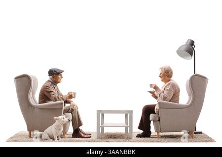 Ältere Ehemann und Ehefrau sitzen in Sesseln mit ihrem Hund und trinken Kaffee isoliert auf weißem Hintergrund Stockfoto