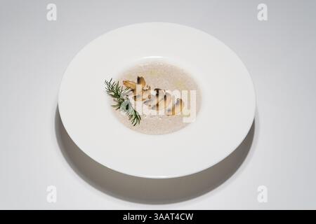 Elegante Gourmet-cremige Pilzsuppe mit Kräutern in der weißen Schüssel. Stockfoto