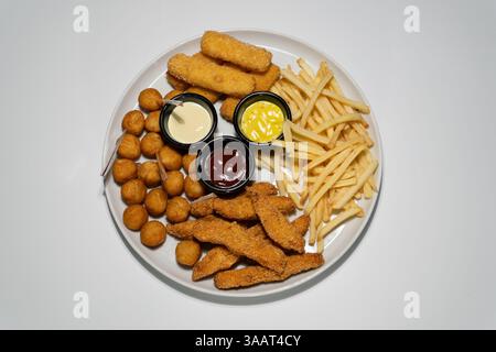 Köstliche gebratene Essensplatte mit Hähnchenstreifen, Pommes Frites, Mozzarella-Sticks, Kartoffelbällchen und Saucen. Stockfoto
