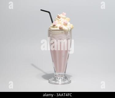 Cremiger rosafarbener Milchshake in Glas mit Schlagsahne, Marshmallows und Strohhalm isoliert auf hellem Hintergrund. Stockfoto