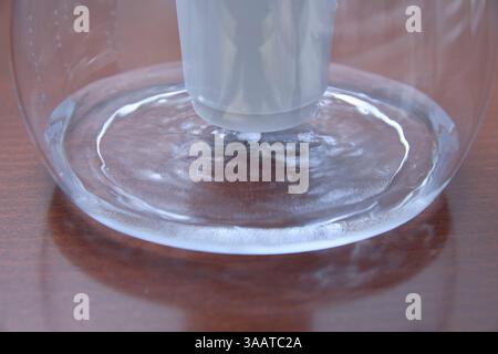 Nahaufnahme eines Wassers, das unter einem Filter in einem Glasbehälter wirbelt. Das Bild zeigt die Interaktion zwischen Wasser und Filtration und zeigt Flüssigkeit Stockfoto