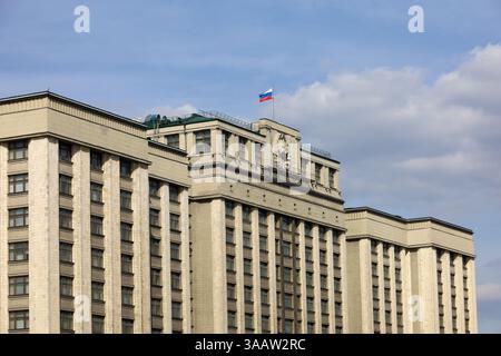 Russische Flagge auf dem Parlamentsgebäude in Moskau vor blauem Himmel mit Wolken. Fassade der russischen Staatsduma, russische Autorität Stockfoto