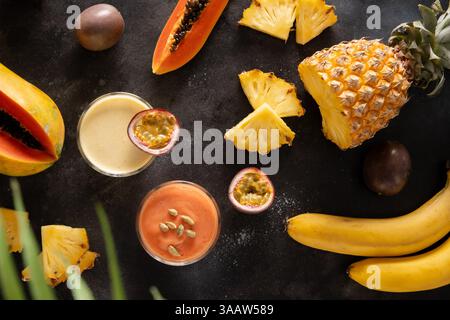 Indische Früchte Lassi. Ananas, Papaya Lassi oder Smoothie in Gläsern auf schwarzem Hintergrund. Beliebtes asiatisches Getränk aus Joghurt, Wasser, Obst und Eis Stockfoto