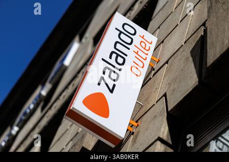 Karlsruhe, Deutschland. März 2025. Am 28.03.2025 ist die Zalando-Schrift und das Markenlogo an der Fassade oberhalb des Eingangs zu einem Outlet-Store der Modemarke im Zentrum von Karlsruhe (Baden-Württemberg) zu sehen. Die Zalando SE mit Sitz in Berlin ist ein börsennotiertes deutsches Online-Versandunternehmen für Schuhe, Bekleidung, Kosmetik und Accessoires. Das Unternehmen ist in mehreren Geschäftsbereichen tätig, von Online-Shops über eigene Marken und stationäre Verkaufsstellen bis hin zu Logistik- und Marketingdienstleistungen für den Einzelhandel. Quelle: Matthias Balk/dpa/Alamy Live News Stockfoto