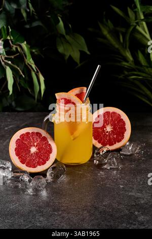 Erfrischender Cocktail aus Grapefruit und Rosmarin mit Eis. Sommergetränk. Grapefruit Limonade in einem Glas auf dunklem Hintergrund. Maurerglas Stockfoto