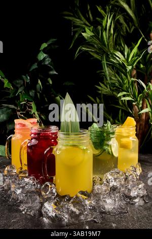 Verschiedene limonaden in einmachgläsern mit Beeren und Früchten. Sommerlimonade in einem Glas mit Eis auf dunklem Hintergrund Stockfoto