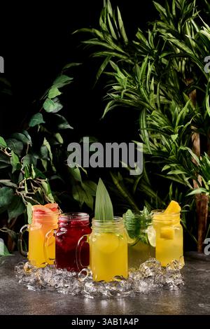 Verschiedene limonaden in einmachgläsern mit Beeren und Früchten. Sommerlimonade in einem Glas mit Eis auf dunklem Hintergrund Stockfoto