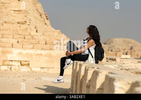 Kairo, Ägypten; 20. Januar 2024: Erleben Sie die antike Majestät, während ein Tourist die Zoser-Stufenpyramide in Sakkara, Ägypten, bestaunt. Erkunden Sie die Geschichte. Stockfoto