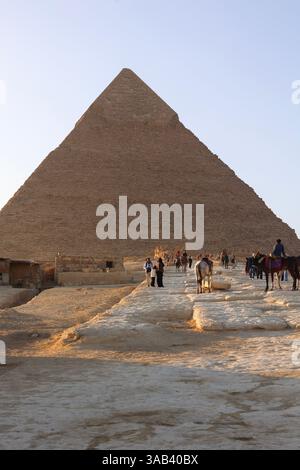 Touristen, die den Weg unter der Großen Cheops-Pyramide des Gizeh-Pyramidenkomplexes in Ägypten entlang laufen Stockfoto