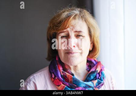 Porträt einer lächelnden Reifen Frau in farbenfrohem Schal, Nahaufnahme mit natürlichem Licht. Stockfoto