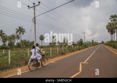 27. März 2015 - Halbinsel Jaffna, Sri Lanka - Tamil Schulmädchen fahren entlang der Straße in Richtung Vasavilan Ost, die 2015 wieder für die Öffentlichkeit geöffnet wurde. Der Sri-lankische Bürgerkrieg begann am 23. Juli 1983 und war ein Aufstand gegen die Regierung der Liberation Tigers of Tamil Eelam (LTTE oder Tamil Tigers), die für einen unabhängigen tamilischen Staat Tamil Eelam kämpften. Nach einem 26-jährigen Krieg und schätzungsweise 40.000 zivilen Toten besiegte die srilankische Armee am 2009. Mai die Tamil Tigers. Viele Tamilen wurden während des 26-jährigen Krieges vertrieben, ihr einst vielversprechendes Land verwüstete über die Jahre und die SR Stockfoto