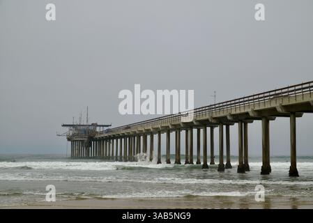 Wellen schlagen an einem bewölkten Tag sanft gegen den Scripps Pier in La Jolla und schaffen eine ruhige Küstenlandschaft. Stockfoto