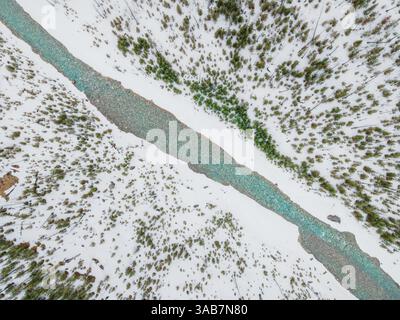 Ein atemberaubender Gletscherfluss schlängelt sich durch zerklüftetes Berggelände mit unberührtem blauem Wasser und dramatischer alpiner Landschaft. Stockfoto
