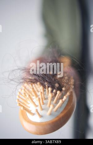 Mit Strängen gefüllte Haarbürste in Nahaufnahme auf hellem Hintergrund Stockfoto