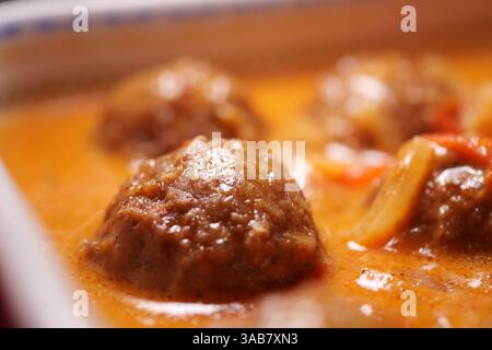 Fleischbällchen, die in reichhaltiger Sauce in einer gemütlichen Küche kochen Stockfoto