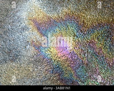 Benzin verschüttet auf Asphalt. Farbige Flecken von einem Benzin auf der nassen Straße. Umweltverschmutzung. Stockfoto