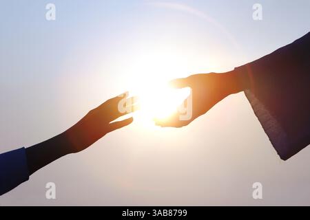 Hand der Erlösung, christliche Hand streckt zur Hand Jesu Christi, helle Sonnensilhouette Stockfoto