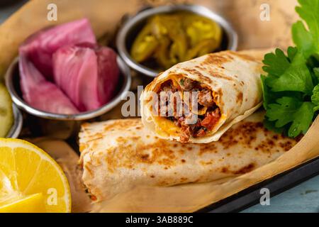 Türkischer Kebab Tantuni serviert mit Sauce und Gurken. Mersin Tantuni-Verpackung Stockfoto