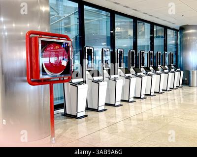 Eine Reihe von Selbstbedienungskiosken in moderner Flughafenumgebung sowie eine Brandschutzschlauchhaspel. Die Szene spiegelt Effizienz und Sicherheit im Flugreisen wider Stockfoto