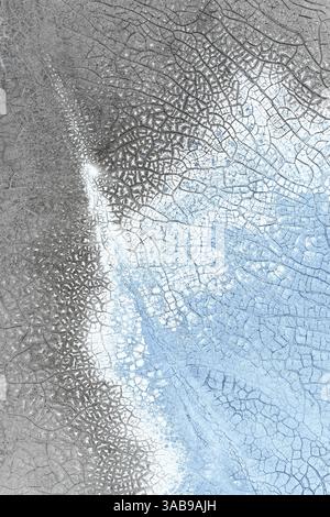 Nahaufnahme einer abstrakten Eisfläche mit komplexen Rissmustern in Grau- und Blautönen, die natürliche Texturen und ein fraktales Design zeigen Stockfoto