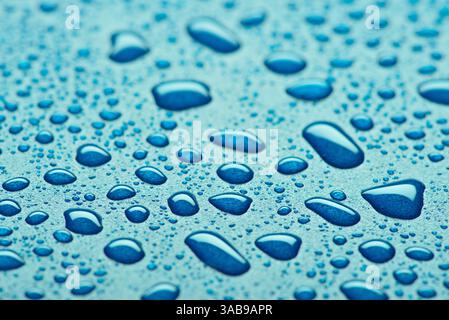 Ein beeindruckendes Nahaufnahme-Bild mit glitzernden blauen Wassertropfen auf einer strukturierten Oberfläche. Die Tropfen variieren in der Größe, was die natürliche Schönheit unterstreicht Stockfoto