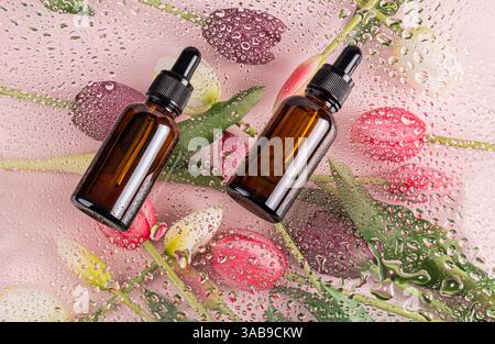 Braune Glastropfenkosmetik liegt auf einem floralen Hintergrund, der mit bunten Tulpen und Wassertropfen geschmückt ist. Perfekt für Themen wie Entspannung, Schönheit, und Stockfoto