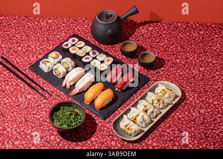 Aufnahme eines japanischen Esstisch mit Sushi, Knödeln und Tee, aufgenommen mit starker Richtungsbeleuchtung für einen lebendigen und appetitlichen Look Stockfoto
