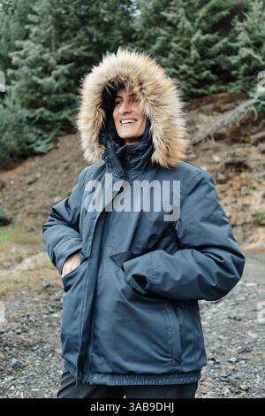 Eine Frau im Wintermantel lächelt herzlich über die malerische Landschaft des Skigebietes Astun in den Huesca Pyrenäen. Sie fängt das Wesen des Winters ein Stockfoto