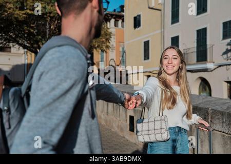 Ein fröhliches junges Paar schlendert Hand in Hand durch die charmanten Straßen von Calatrava, Mallorca, Spanien, auf der Suche nach ihrem idealen Urlaubsziel Stockfoto