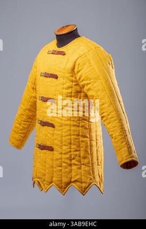 Gelbe Gepolsterte Gambeson-Jacke. Gesteppte Unterpanzerung im Mittelalter mit Lederriemen. Stockfoto