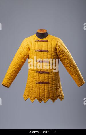 Gelbe Gepolsterte Gambeson-Jacke. Gesteppte Unterpanzerung im Mittelalter mit Lederriemen. Stockfoto