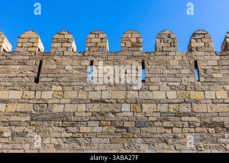 Historische Steinmauer mit Zinnen und Pfeilschlitzen, die mittelalterliche Architektur der Festung Baku, einem mittelalterlichen Gebäude in Baku, Aserbaidschja, zeigt Stockfoto