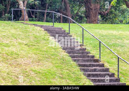 Kurze, zementierte Treppen mit Metallgeländer führen einen grasbewachsenen Hang auf der Insel Corregidor auf den Philippinen hinauf Stockfoto