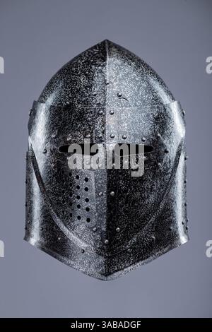 Geschlossener mittelalterlicher Ritterhelm mit kleinen Perforationen. Dieses Bild zeigt einen geschlossenen mittelalterlichen Ritterhelm, wahrscheinlich aus Stahl, mit einer spitzen Spitze Stockfoto