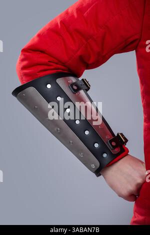 Nahaufnahme der silbernen Schienenkarmbänder auf roter gepolsterter Rüstung. Dieses Bild zeigt eine Nahaufnahme von silbernen Metallschienen, die über einem rot gepolsterten Kleidungsstück getragen werden. Stockfoto