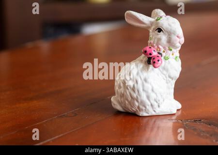 Weißes Kaninchen mit einer Marienkäfer-Figur auf einem Holztisch in Boracay, Philippinen Stockfoto