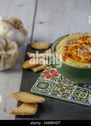 Schöne Schüssel Hummus, traditionelles vegetarisches Gericht aus dem Nahen Osten auf Basis von Kichererbsen, gewürzt mit Olivenöl und Paprika Stockfoto